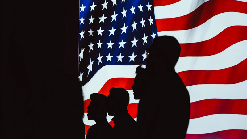 Photo of military personnel in front of a U.S. Flag